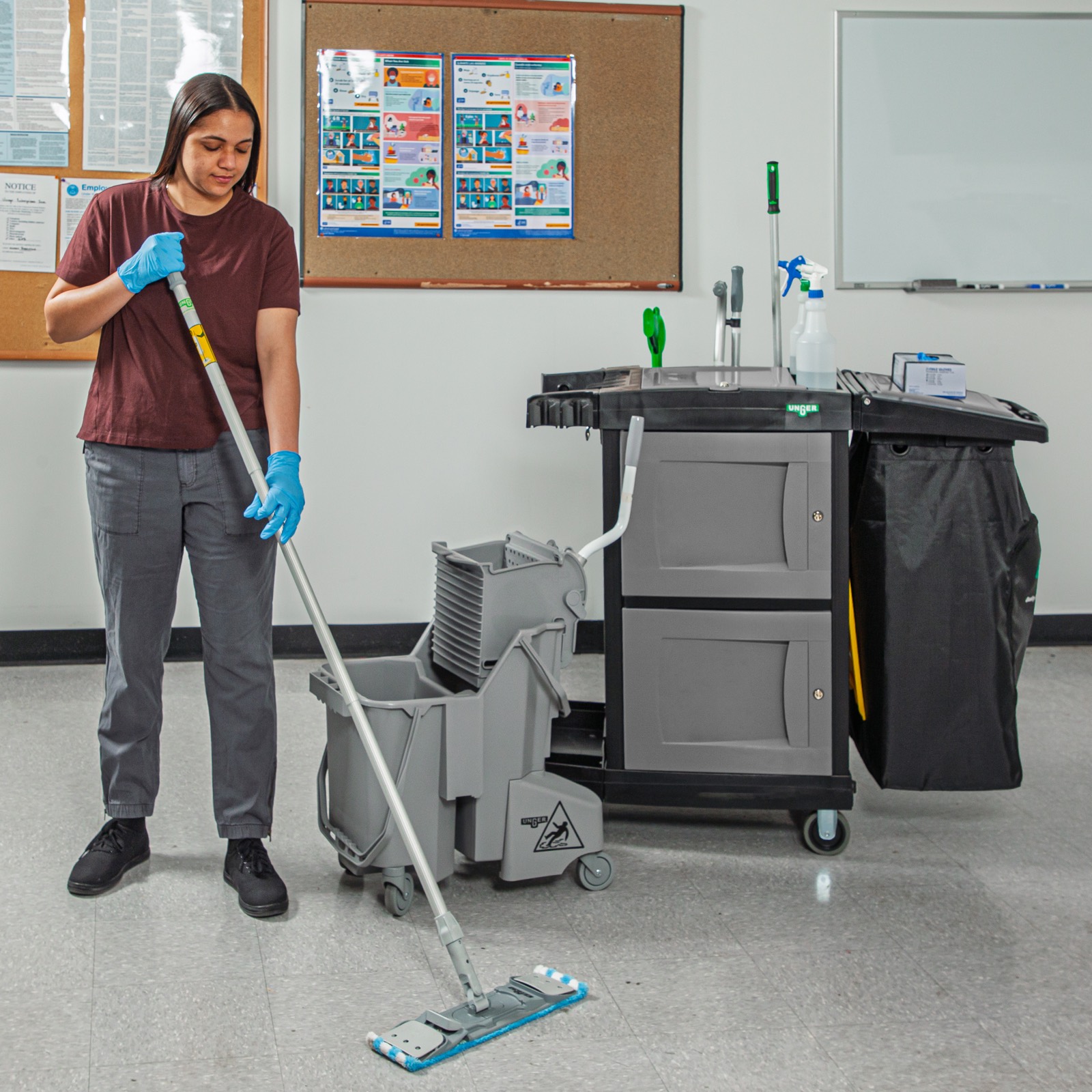 Cleaner mopping a classroom floor beside a CleanRx cart